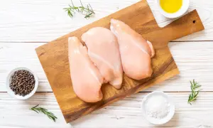 Tre petti di pollo crudi su tagliere, con pepe nero, sale, rosmarino e olio. Ideale per un pasto leggero, con poche calorie petto di pollo.