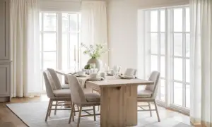 Ljus och luftig matplats med inspiration från naturen. Träbord, beiga stolar och stora fönster med vita gardiner skapar en harmonisk känsla.