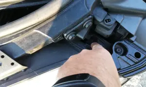 Palec wskazuje śrubę mocującą reflektor podczas wymiany żarówki audi a4 b7 przód prawa.