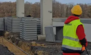 Pomocnik elektryka w kamizelce odblaskowej na budowie.