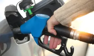Tankowanie samochodu, ręka trzymająca niebieski pistolet paliwowy. Rosnące ceny paliwa w Europie wpływają na portfele kierowców.