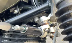 Amortyzator skrętu motocykl, zamontowany obok chłodnicy, zapewnia stabilność kierownicy podczas jazdy.