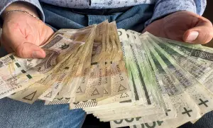 Dłoń trzyma plik banknotów. Czy darowizna a podatek to temat, który Cię interesuje?