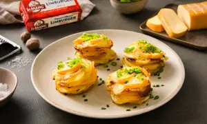 Gestapelte Kartoffeln mit geschmolzenem Käse und Schnittlauch. Daneben ein Block Limburger Käse, bereit für ein Romadur-Gericht.