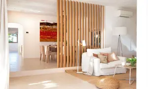 Una solución para como hacer una pared divisoria económica: listones de madera separan el salón del comedor, creando un ambiente moderno y luminoso.