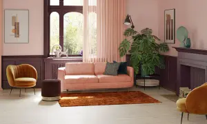 Przytulny salon z sofą w kolorze pudrowy róż, aksamitnym fotelem i dywanem w odcieniu cegły.