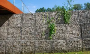Kamienna skarpa na granicy działki, porośnięta zielenią, stanowi solidne umocnienie terenu.