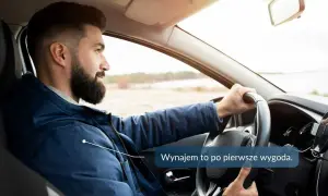 Mężczyzna z brodą prowadzi samochód, trzymając kierownicę.