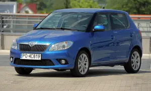 Niebieska Skoda Fabia 2, z nowymi żarówkami w reflektorach, parkuje na placu.