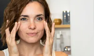 Une femme applique une crème sur son visage, découvrant les premières rides.