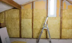 Ocieplanie ściany od wewnątrz: wełna mineralna w drewnianej konstrukcji, drabina i materiały budowlane.