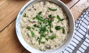 Kremowe risotto z grzybami, przygotowane w Thermomixie, posypane świeżą natką pietruszki. Idealne danie na obiad.
