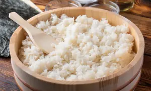 Gotowany ryż do sushi w drewnianym naczyniu z drewnianą łyżką.
