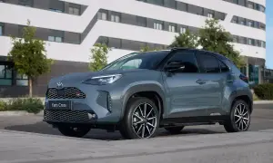 Szary Toyota Yaris Cross benzyna z czarnymi akcentami stoi przed nowoczesnym budynkiem.