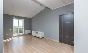 Nowe mieszkanie TBS z jasnym drewnianym parkietem, szarymi ścianami, białym meblem i drzwiami.