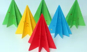 Kolorowe choinki origami płaskie z życzeniami. Zielone, żółte, czerwone i niebieskie ozdoby świąteczne.