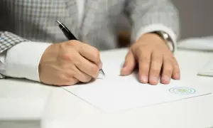 Mężczyzna w garniturze wypełnia dokument, być może wniosek kw-wpis wzór wypełnienia spadek.