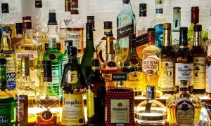 Różnorodne rodzaje alkoholi: whisky, likiery, gin, brandy i inne, stojące na półce.