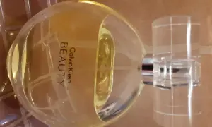Flakon perfum Calvin Klein Beauty 100 ml, o bursztynowym kolorze, stoi na brązowym tle.