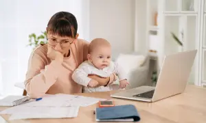 Mère pensive avec bébé, jonglant entre le travail et le renouvellement congé parental CAF.