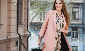 Elegancka kobieta w pastelowym płaszczu i kwiecistej sukience. Idealny strój na 14 stopni, gdy chcesz wyglądać stylowo.