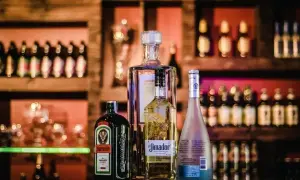 Butelka Jägermeistera, z etykietą informującą o zawartości alkoholu, stoi obok innych alkoholi.