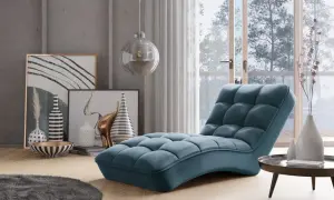 En lyxig, blå schäslong fåtölj med quiltad design står i ett modernt vardagsrum med konst och en stor fönsterdörr.