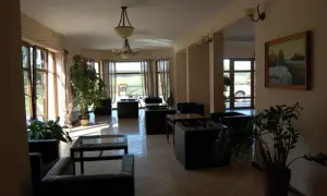 Wnętrze rezydencji nad Wigrami. Wygodne fotele i stoliki tworzą przytulną przestrzeń. Duże okna wpuszczają mnóstwo światła.
