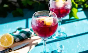Två glas med tinto de verano, fyllda med is och citronklyftor, står på ett blått bord.