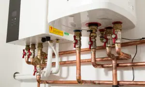 Instalacja grzewcza z pompą ciepła. Widoczne miedziane rury, zawory i przyłącza do istniejącej instalacji.