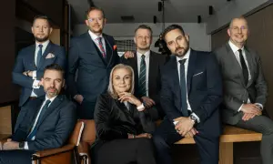 Grupa siedmiu profesjonalistów w garniturach, pozujących do zdjęcia.