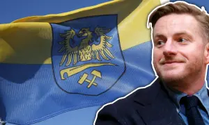 Szczepan Twardoch na tle flagi z godłem Górnego Śląska.