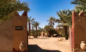 Ein Tor führt zu einem Campingplatz in Marokko, umgeben von Palmen. Ja, ist Marokko sicher für Reisende.