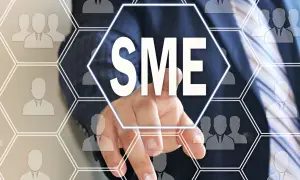 Palec wskazuje na ekran z napisem SME, symbolizującym małego przedsiębiorcę i jego definicję w biznesie.