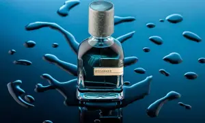 Szklana butelka perfum Megamare otoczona kroplami wody na granatowym tle.