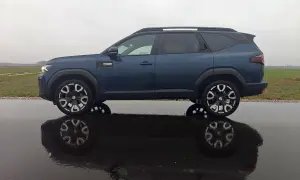Dacia Bigster LPG w ciemnoniebieskim kolorze, zaparkowana na mokrej drodze, z odbiciem w kałuży.