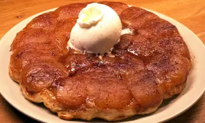 En gyllene tarte tatin med en kula vaniljglass som smälter över de karamelliserade äpplena.