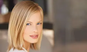 Kobieta z blond włosami w modnym clavi cut, z niebieskimi oczami i delikatnym uśmiechem.