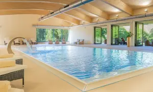 Entspannter Urlaub in Sachsen: Einladender Innenpool mit Wasserfall, Liegen und Blick ins Grüne. Perfekt für erholsame Tage.