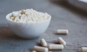 Biały proszek w miseczce i kapsułki. Colostrum na co? Na wsparcie odporności i regeneracji.