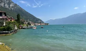 Vista sul lago con montagne sullo sfondo, barche e case colorate. Un vero gargnano geheimtipp.