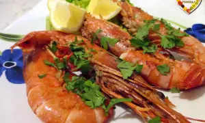 Assiette de gambas grillées, garnie de persil frais et de quartiers de citron. Une belle idée pour une recette gambas légère et savoureuse.