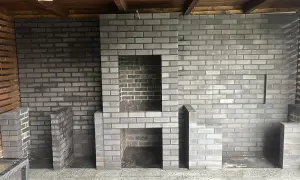 Nowy, murowany prosty grill z cegły czeka na pierwsze rozpalenie. Wygodny, z miejscem na drewno i akcesoria.