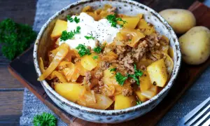 Herzhaftes Schichtkraut Rezept mit Hackfleisch, Kartoffeln und einem Klecks Sauerrahm, garniert mit Petersilie.