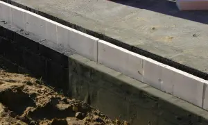 Izolacja fundamentów: biały styropian, czarna hydroizolacja i beton. Jaka grubość styropianu na fundament?