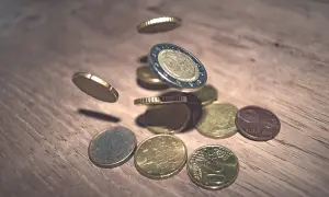 Monety euro spadające na drewniany blat. To waluta Hiszpanii, symbolizująca bogactwo i handel.