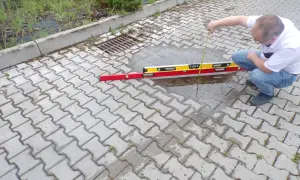 Mężczyzna sprawdza poziom wody na chodniku z kostki brukowej.