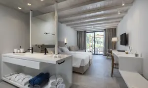Pokój hotelowy z dwoma łóżkami, łazienką i widokiem na taras, idealny na pobyt w Caravia Beach Kos.