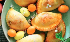 Nepitelle calabresi ricetta originale: dolcetti dorati ripieni, decorati con uova colorate e fiori, un'esplosione di sapori autentici.