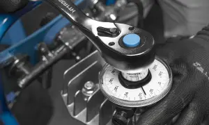 Mano enguantada ajustando una llave dinamométrica con dial para medir el par de apriete. Aprende como usar llave dinamometrica.